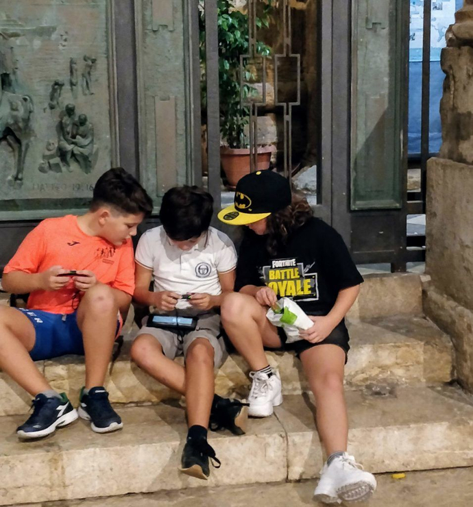 three boys playing on a single switch in the street