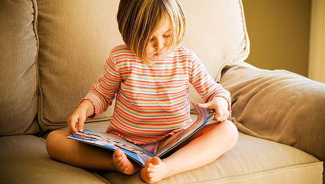A little girl reading in a sofa